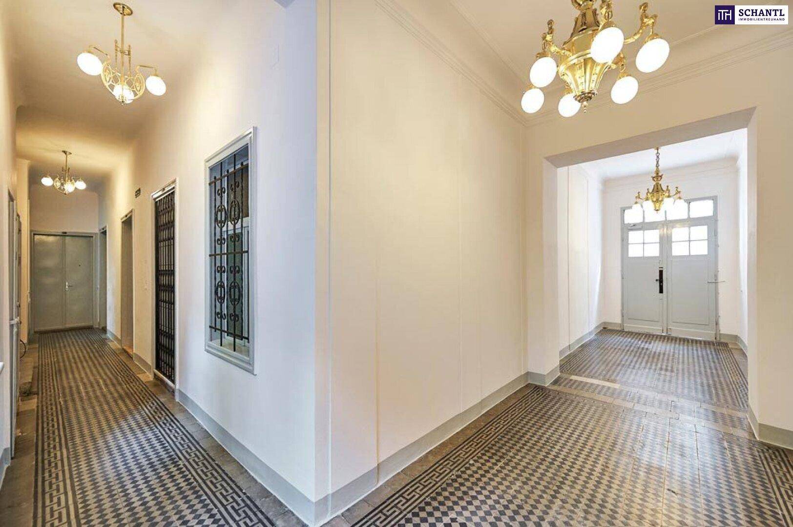 Langer Flur mit historischen Fliesen, hohen Decken und eleganten Deckenleuchten.