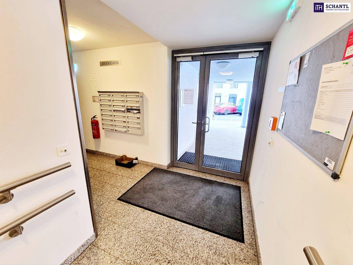 Eingangsbereich eines Mehrfamilienhauses mit Briefkästen und Zugang zur Straße.