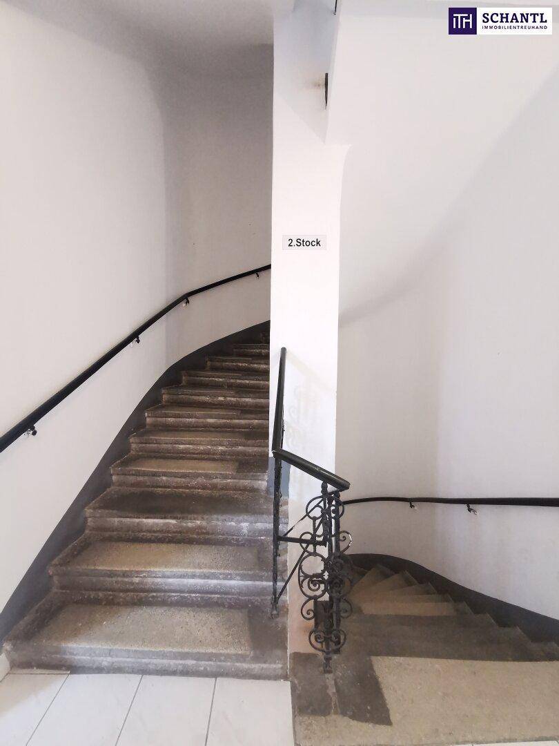 Historisches Treppenhaus mit Steinstufen und schmiedeeisernem Geländer in einem Altbau.