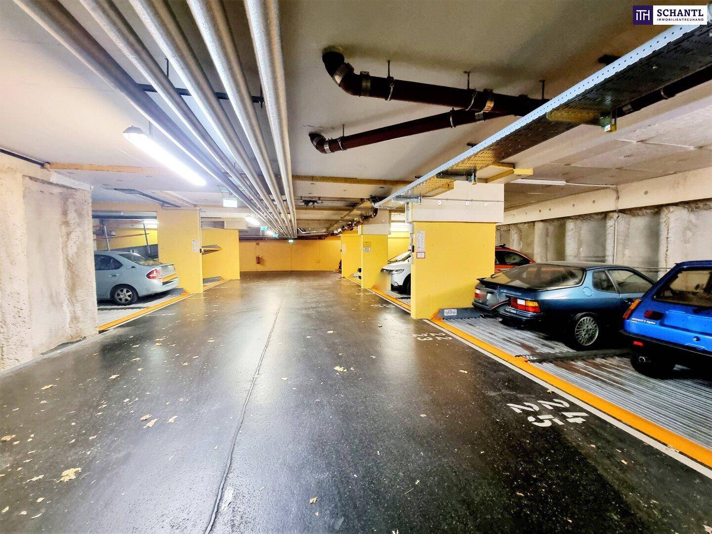 Tiefgarage mit mehreren Stellplätzen und sichtbaren Versorgungsleitungen an der Decke.