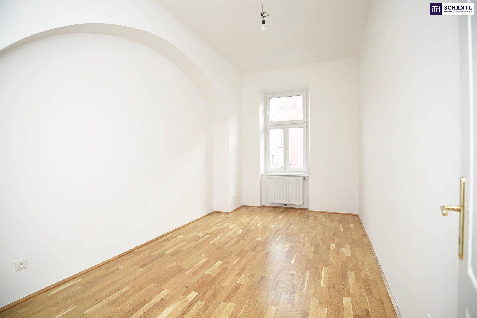 Heller, leerer Raum mit Holzboden und einem Fenster, geeignet als Schlafzimmer.