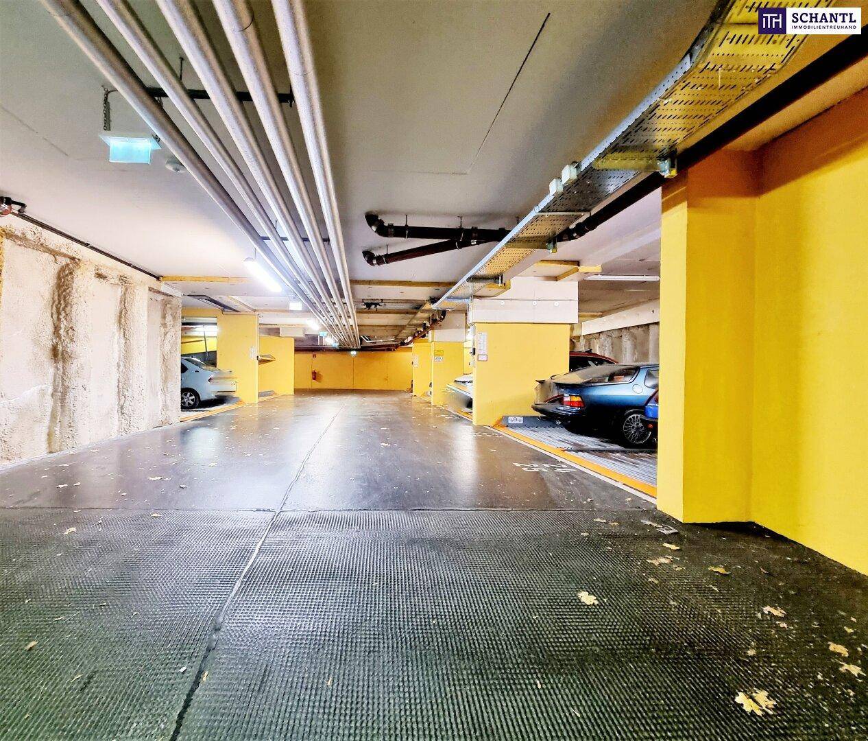 Tiefgarage mit mehreren Stellplätzen und sichtbaren Versorgungsleitungen an der Decke.