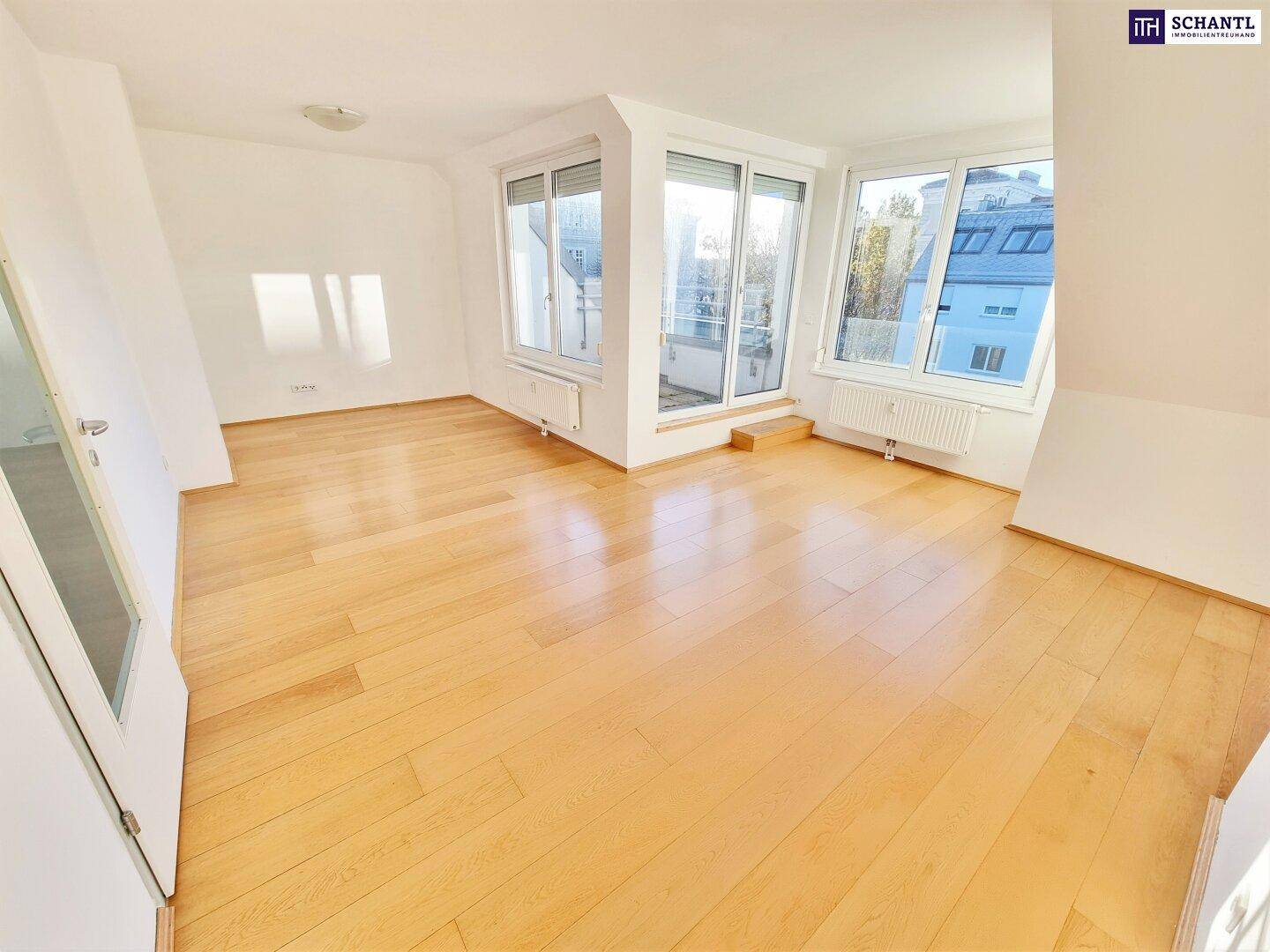 Helles Wohnzimmer mit Holzboden, großen Fenstern und Zugang zu einem Balkon.