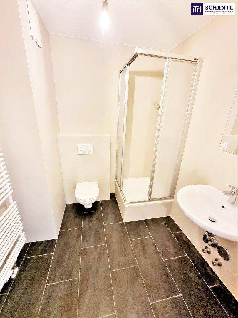 Modernes Badezimmer mit dunklen Fliesen, Duschkabine, WC und Waschbecken.