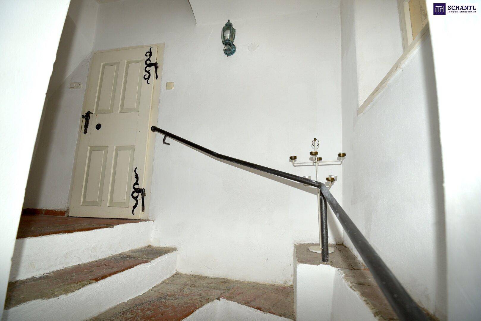 Treppenhaus mit Terrakottafliesen, weiß gestrichenen Wänden und einem schmiedeeisernen Geländer.