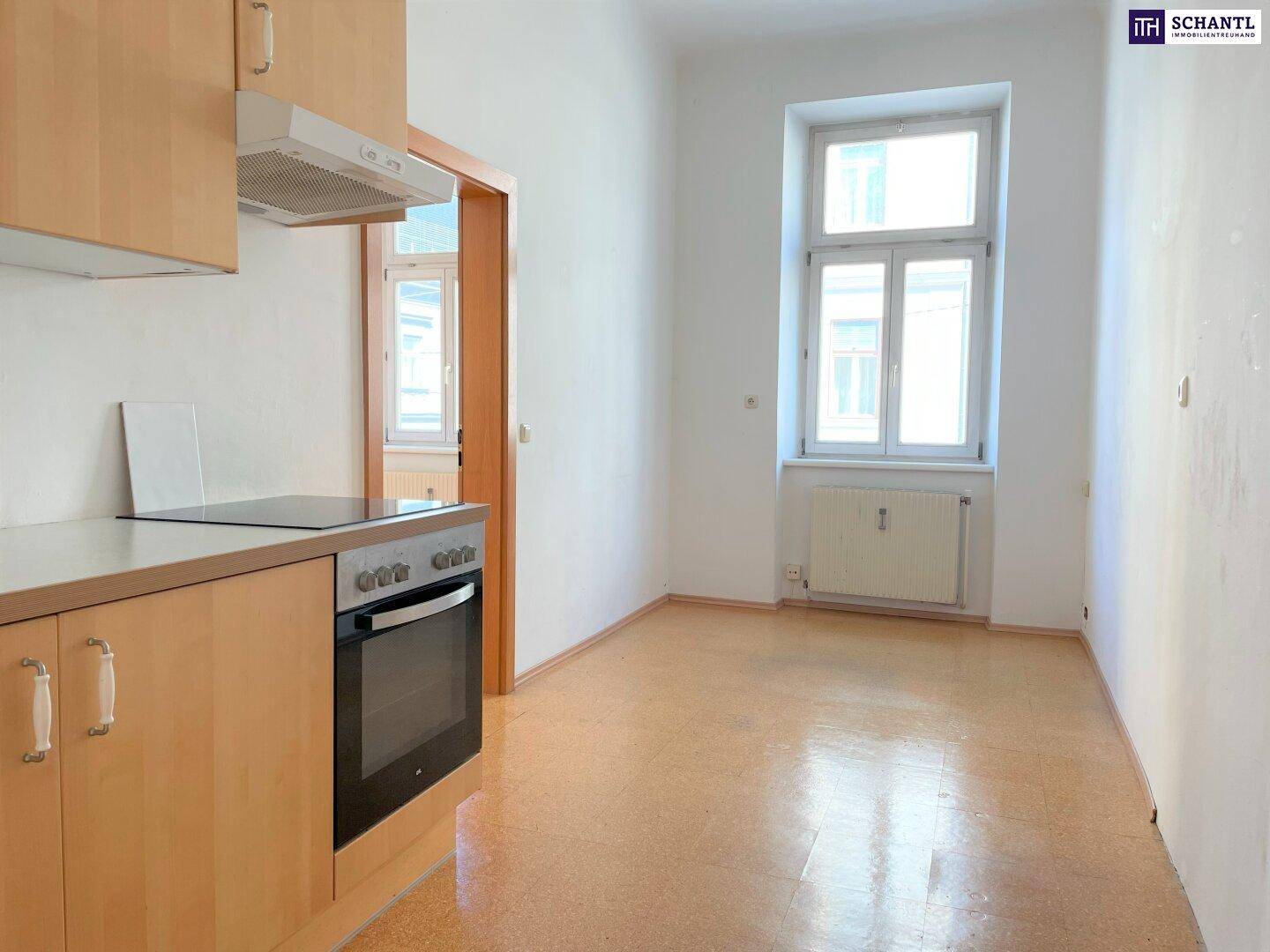 Funktionale Küche mit hellen Holzschränken, Einbauherd und Induktionskochfeld neben einem Fenster.