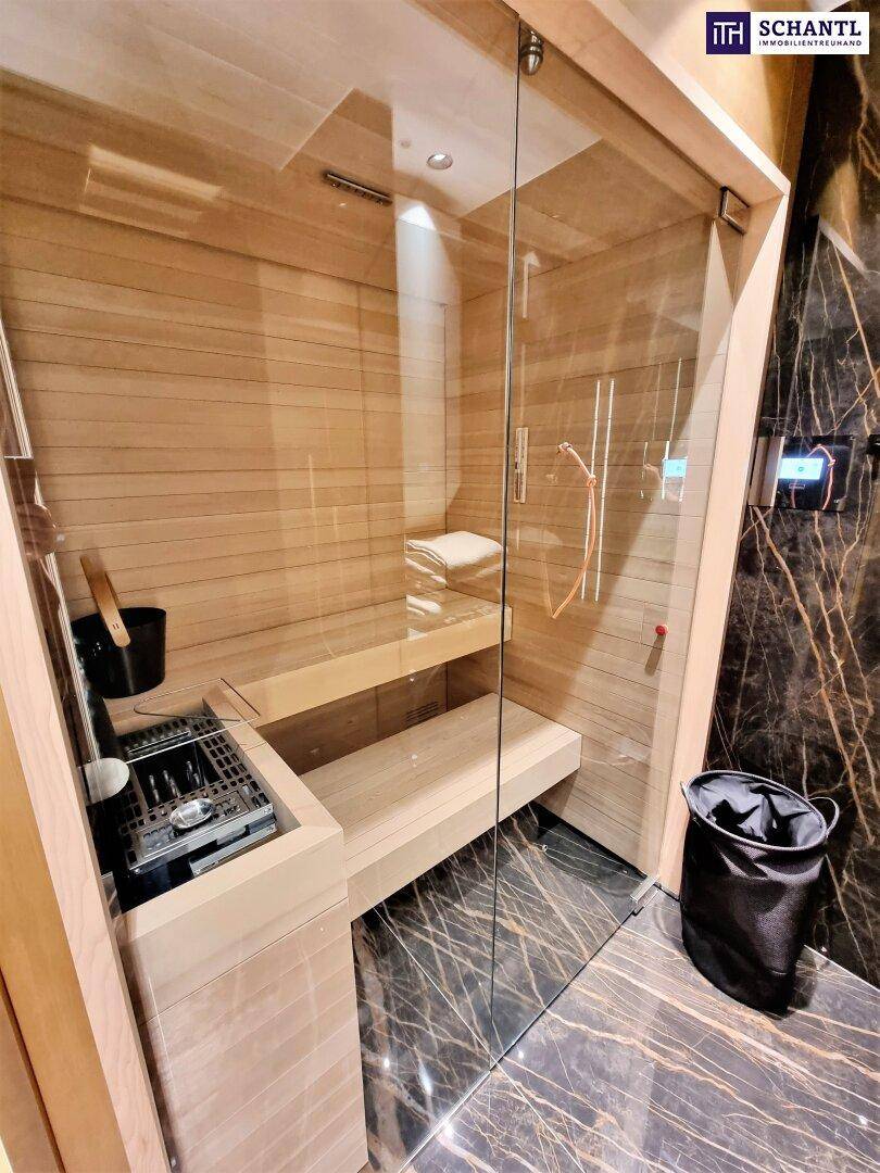 Moderne Sauna mit Holzbänken und Glastür, integriert in ein luxuriöses Badezimmer mit Marmor.