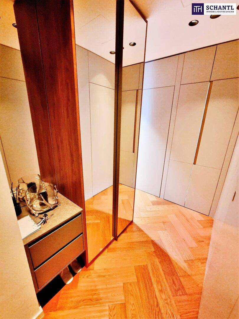 Begehbarer Kleiderschrank mit Einbauschränken, Spiegelsäule und Fischgrätparkettboden.