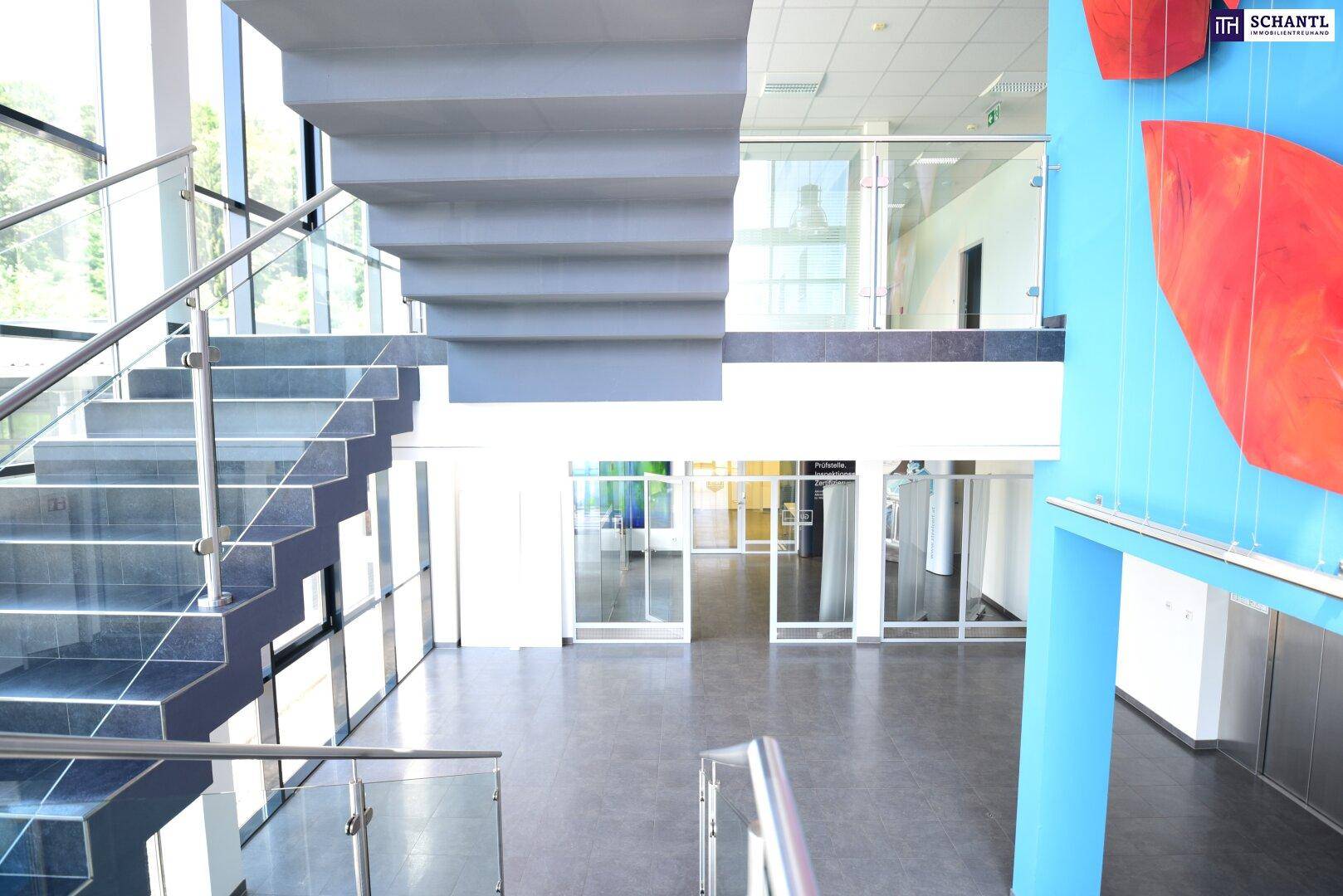 Moderner Eingangsbereich mit eleganter Treppe, Glasgeländer und farbiger Wandkunst.