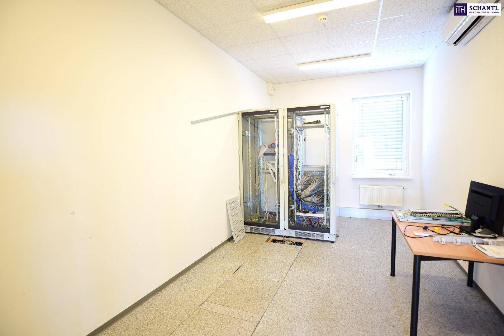 Technikraum mit Serverracks, erhöhtem Boden und einem kleinen Fenster für Belüftung.