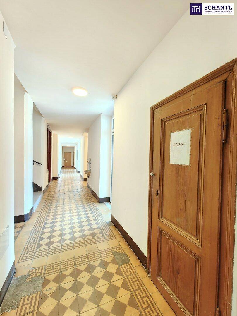 Langer Flur mit charakteristischem Fliesenboden und Holztüren in einem Altbau.