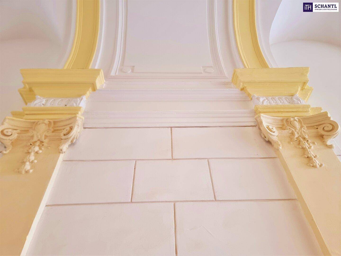 Detailaufnahme der historischen Architektur mit gelben Stuckelementen und hohen Decken im Flur.