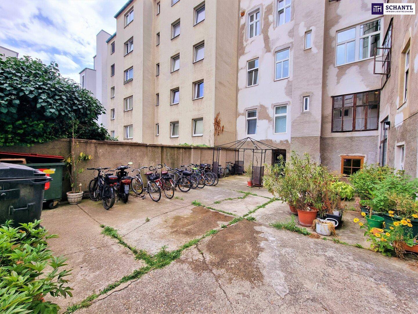 Innenhof mit Fahrradabstellplätzen und Pflanzen, umgeben von Gebäuden, bietet Gemeinschaftsfläche.