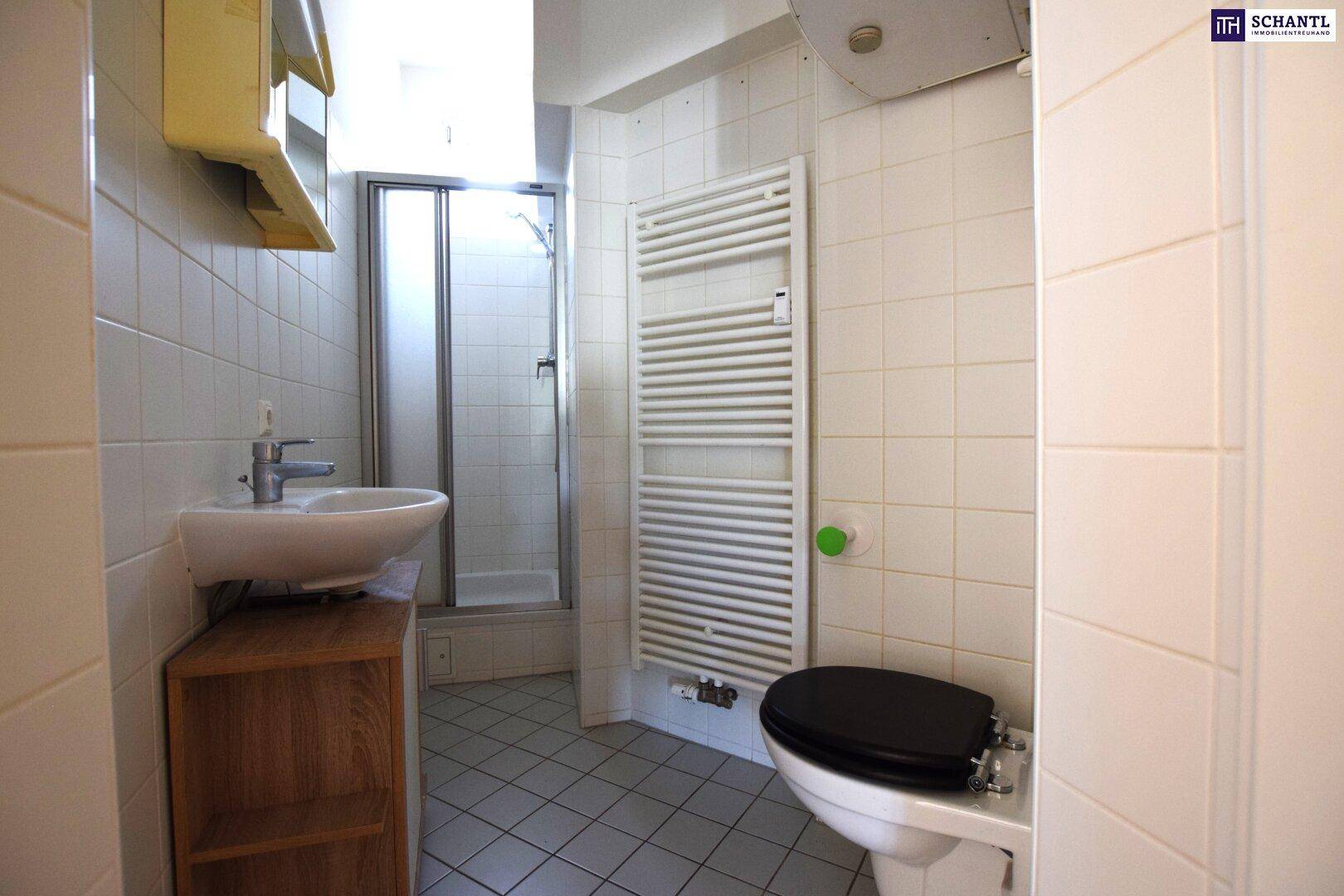 Gefliestes Badezimmer mit Dusche, Waschbecken, Toilette und Handtuchheizkörper.
