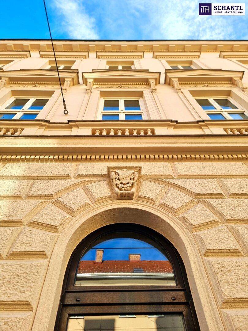 Historische Fassade eines Gebäudes mit dekorativen Elementen und blauer Himmel.