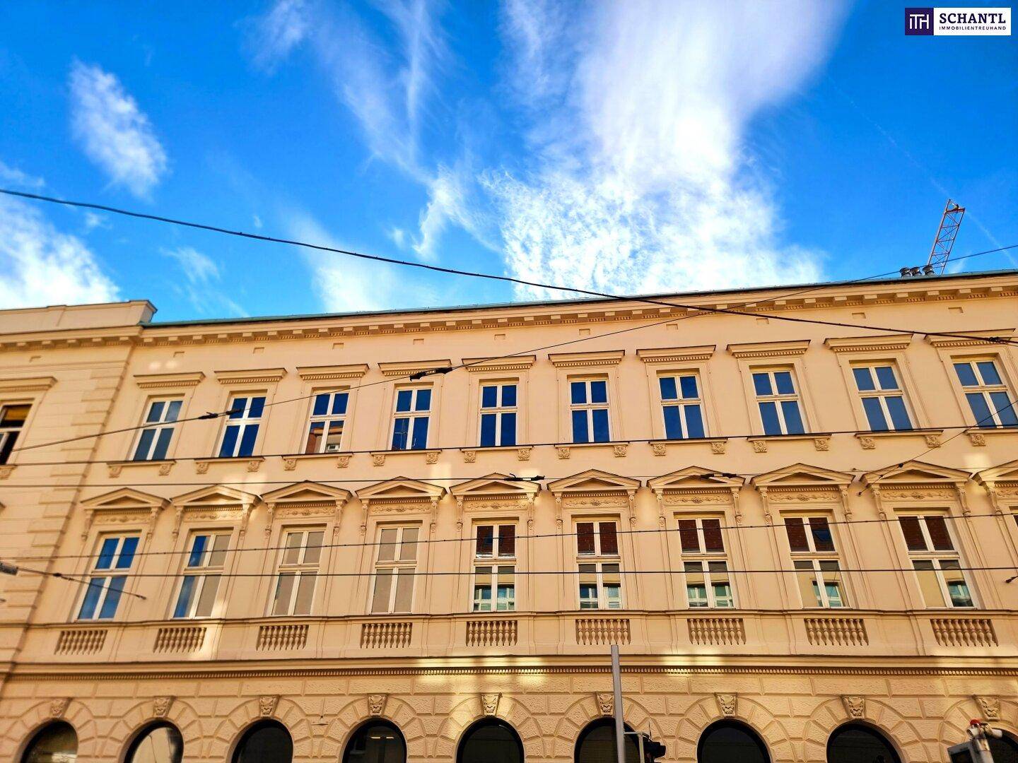 Klassische Gebäudefassade mit vielen Fenstern und einem weiten Blick auf den Himmel.