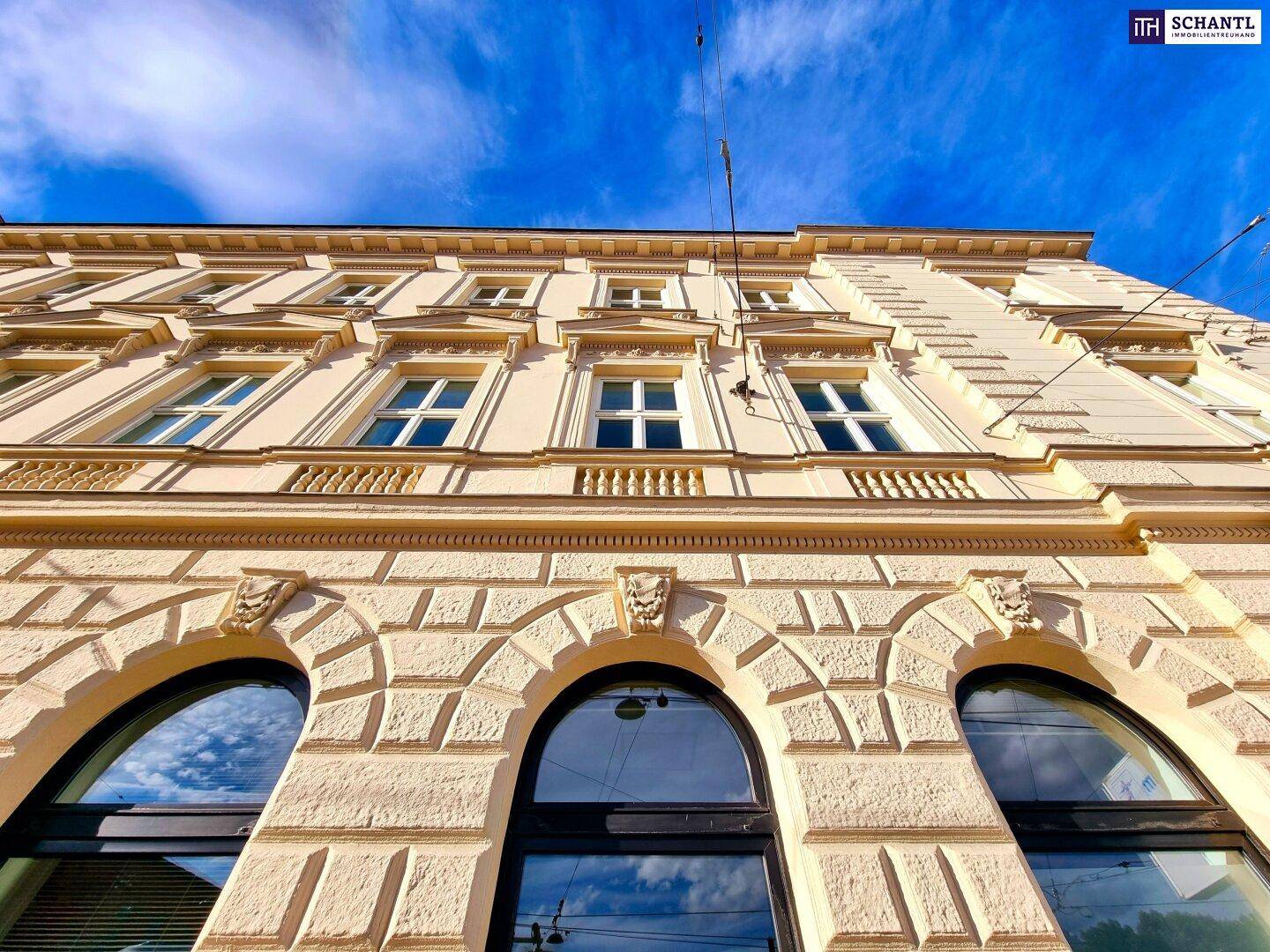 Historische Gebäudefassade mit großen Bogenfenstern und dekorativen Details.