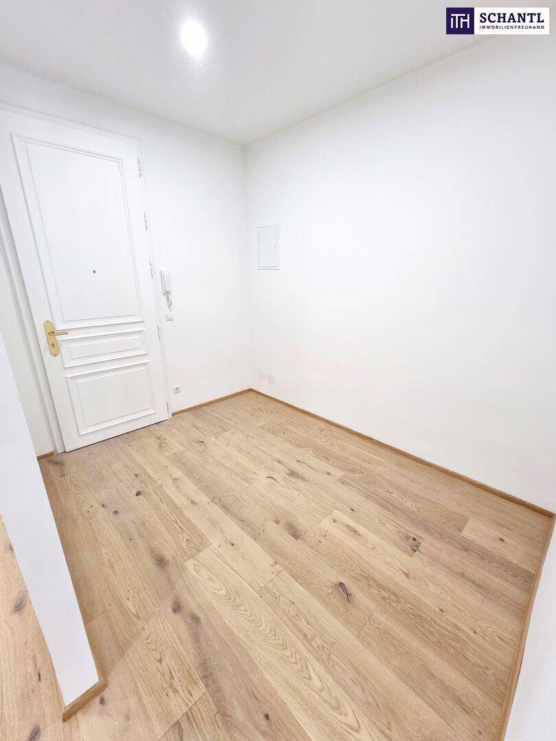 Heller Eingangsbereich mit Parkettboden und weißer Tür, einladend gestaltet.