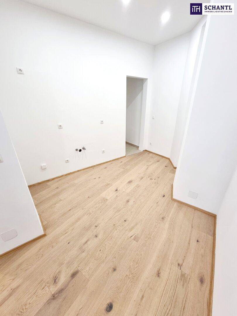 Leerer Raum mit Parkettboden und Anschlüssen für eine zukünftige Küche.