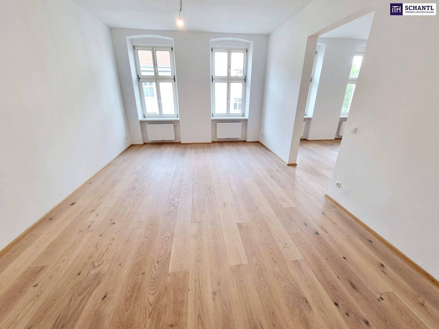 Geräumiges Zimmer mit Parkettboden und großen Fenstern, bietet viel Tageslicht.