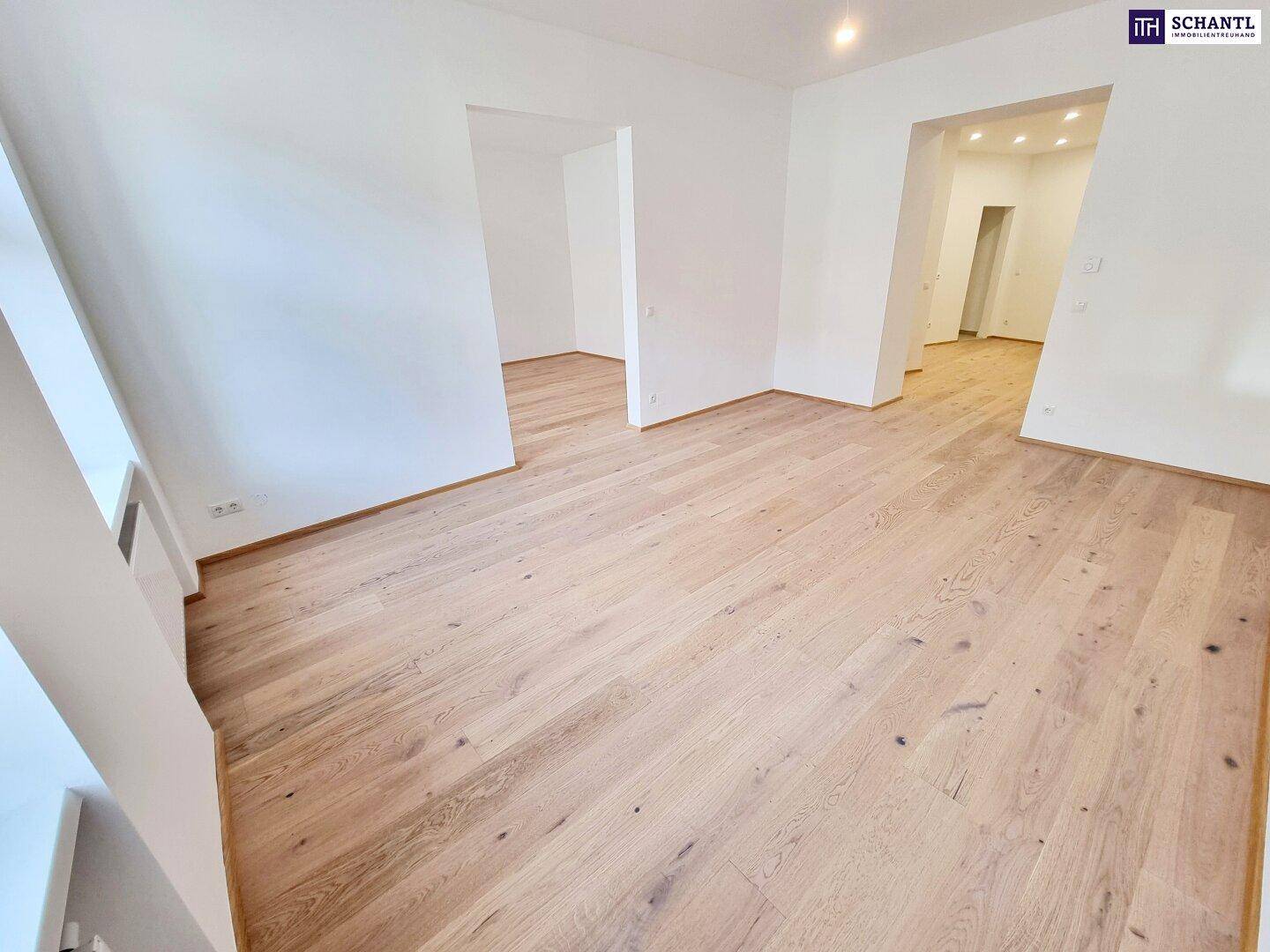 Geräumiges Zimmer mit hellem Parkettboden und Zugang zu weiteren Räumen.