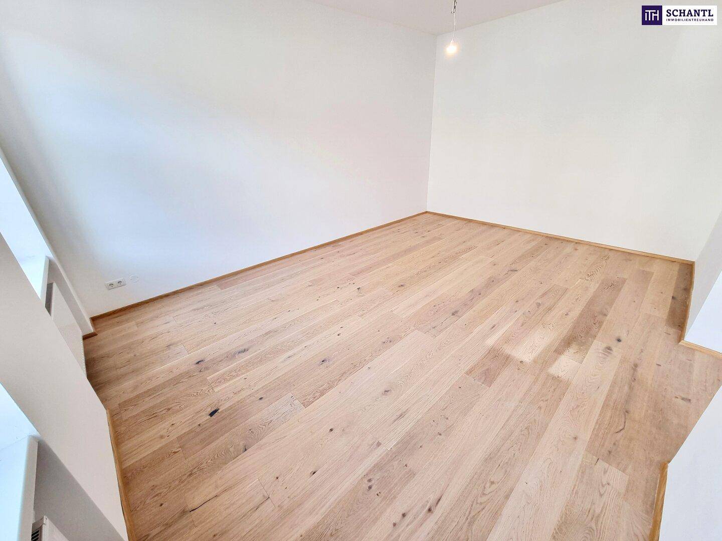 Leeres Zimmer mit hellem Parkettboden und weißen Wänden, bereit zur Nutzung.