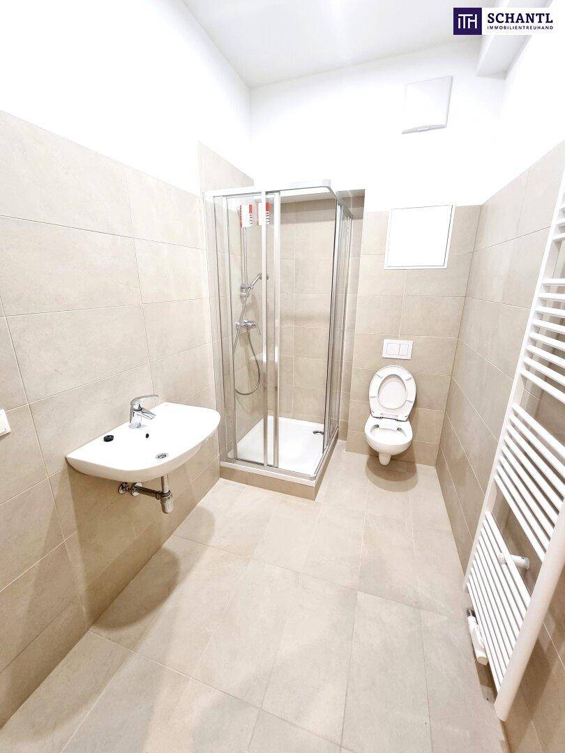 Modernes Badezimmer mit Dusche, WC, Waschbecken und beheiztem Handtuchhalter.