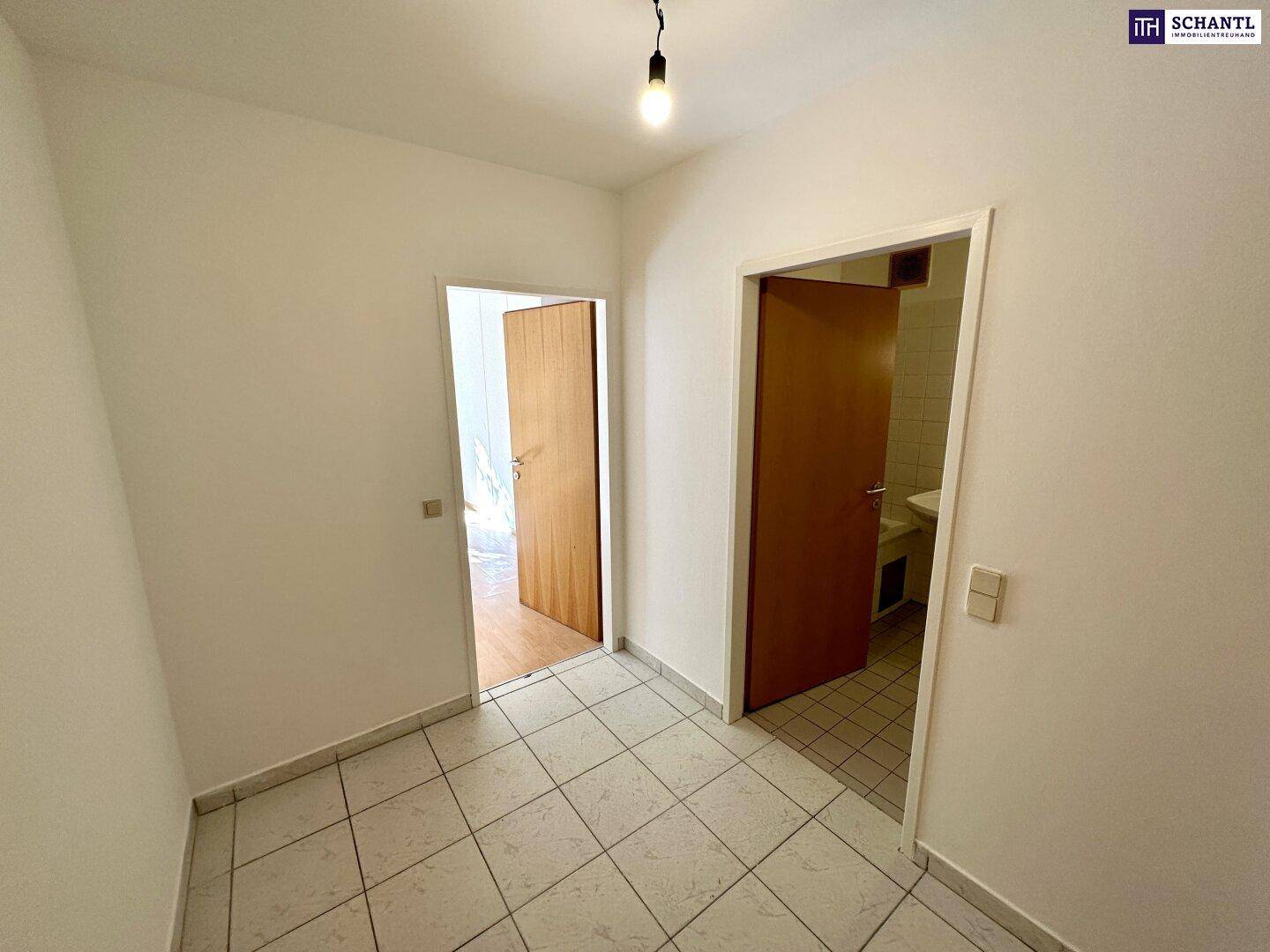 Heller Flur mit Fliesenboden und Zugang zu weiteren Zimmern und dem Badezimmer.