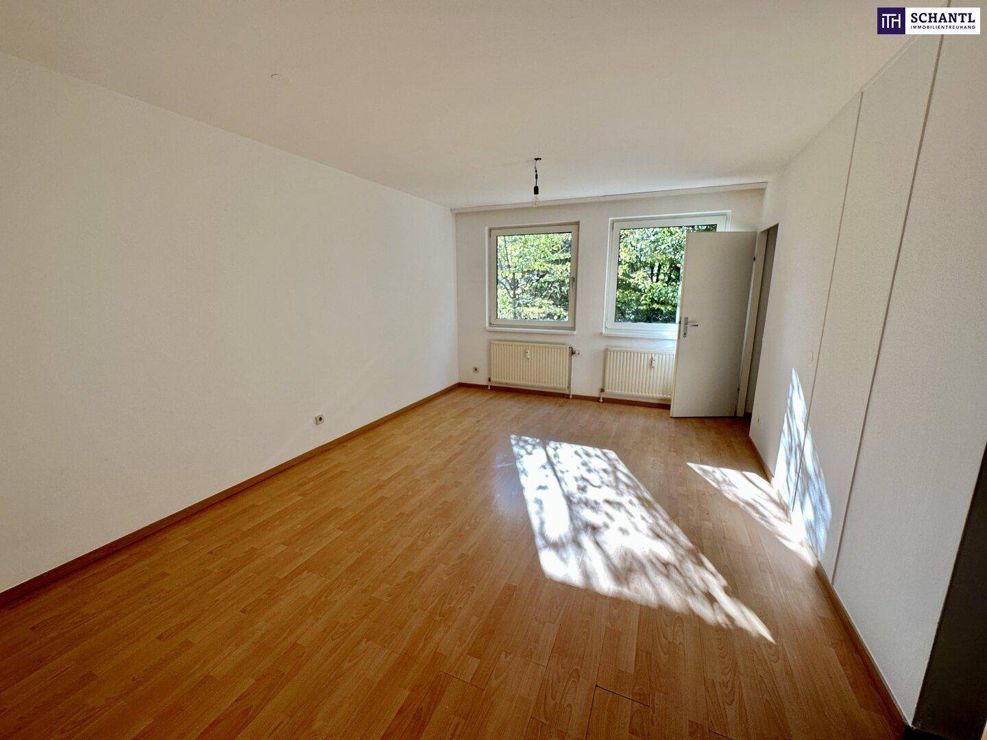 Geräumiges Zimmer mit hellem Parkettboden, großen Fenstern und viel Tageslicht.