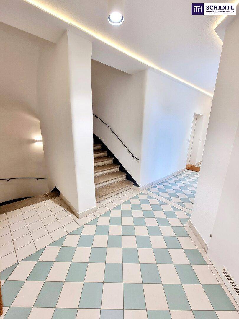 Treppenhaus mit hellen Steinstufen und modernem Fliesenboden im Schachbrettmuster.