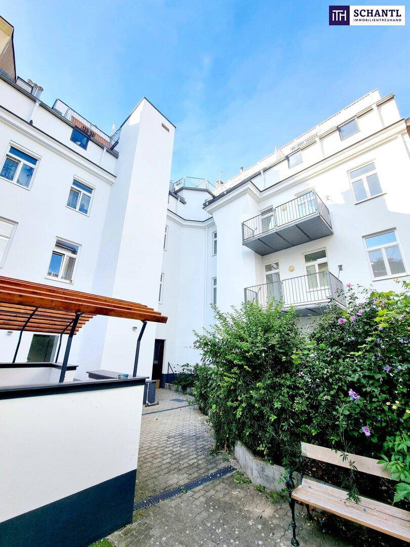 Gepflegter Innenhof mit Sitzbank, grüner Bepflanzung und Gebäudefassaden.