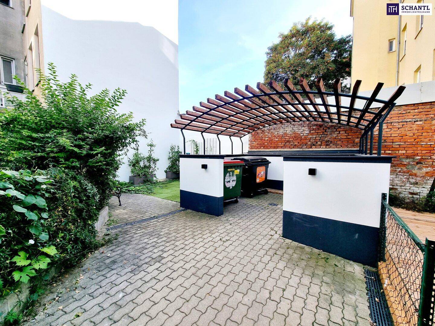 Müllentsorgungsbereich im Freien mit Überdachung und gepflastertem Boden.