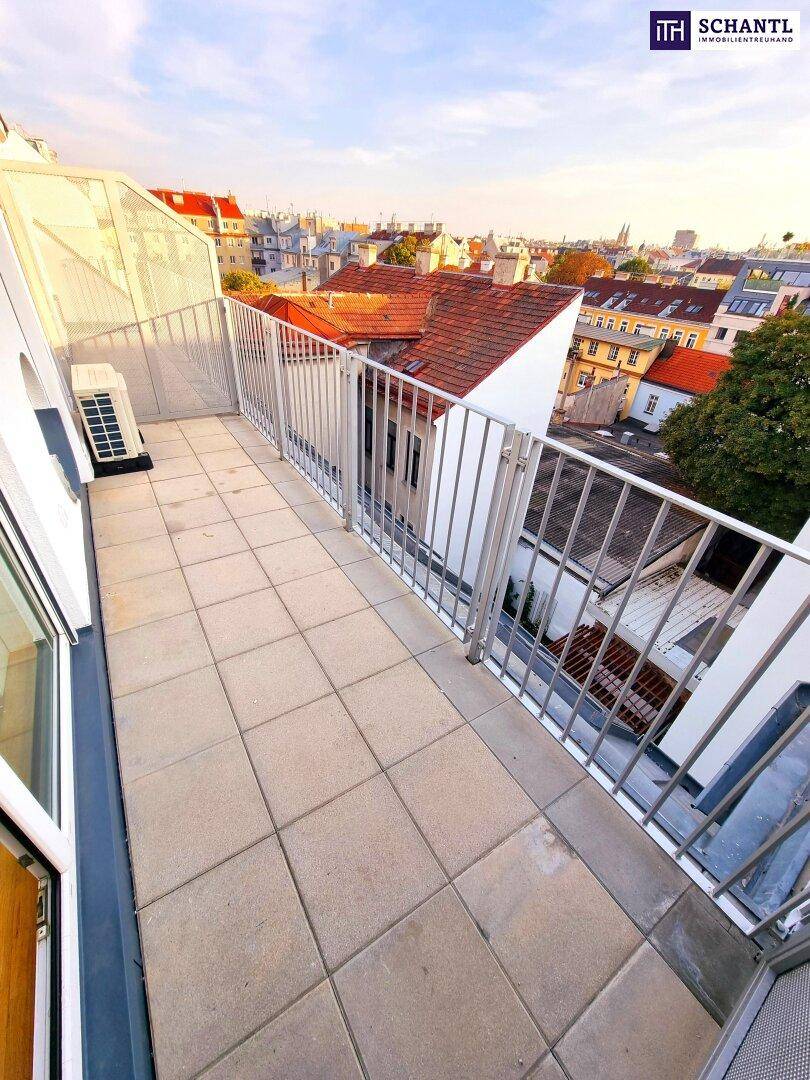 Sonnige Dachterrasse mit Fliesenboden und weitem Stadtblick bei Sonnenuntergang.