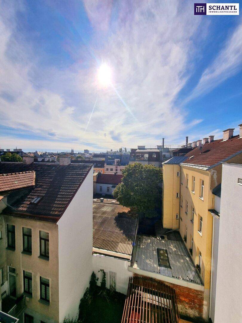 Weite Stadtansicht mit Dächern und Gebäuden unter sonnigem Himmel.