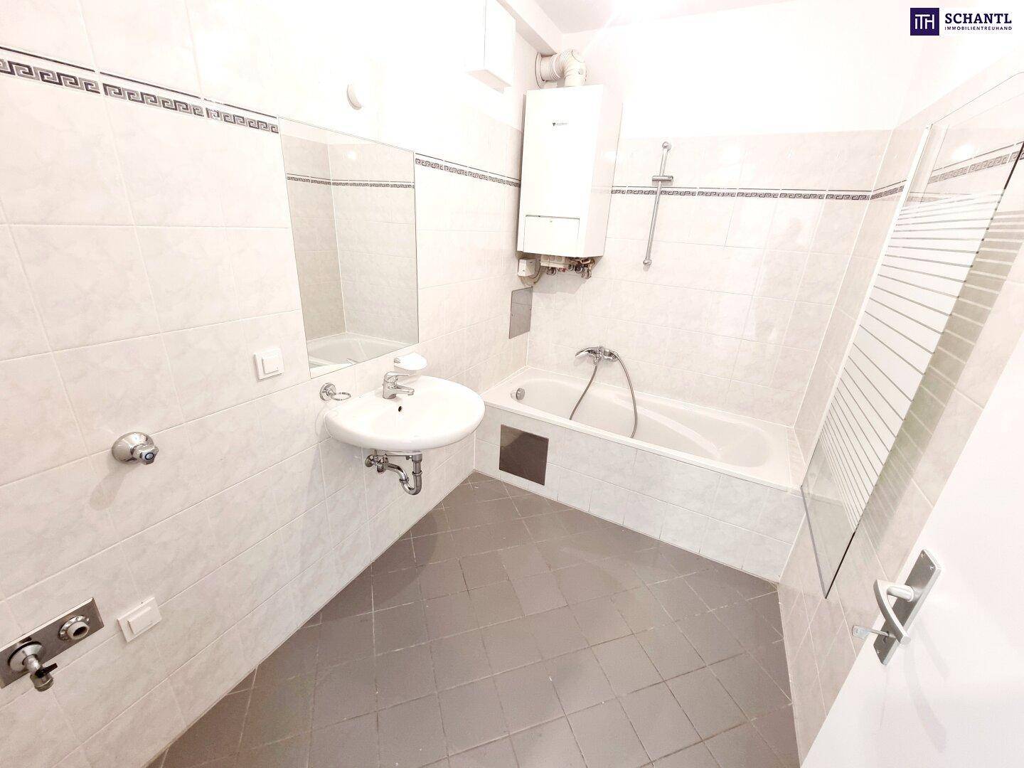 Helles Badezimmer mit Badewanne, Waschbecken und weißen Wandfliesen.