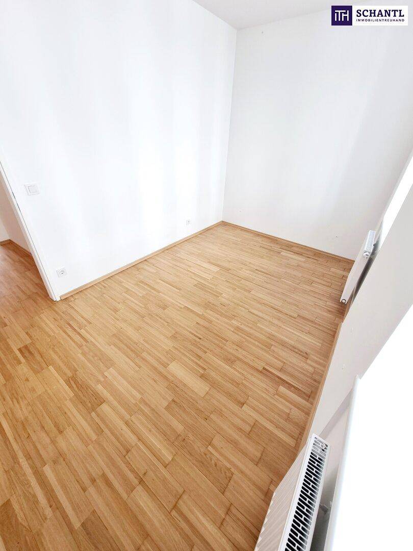 Geräumiges Zimmer mit hellem Parkettboden und viel Tageslicht.