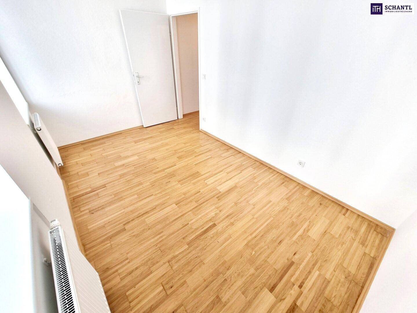 Ruhiges Zimmer mit Parkettboden und weiß gestrichenen Wänden.