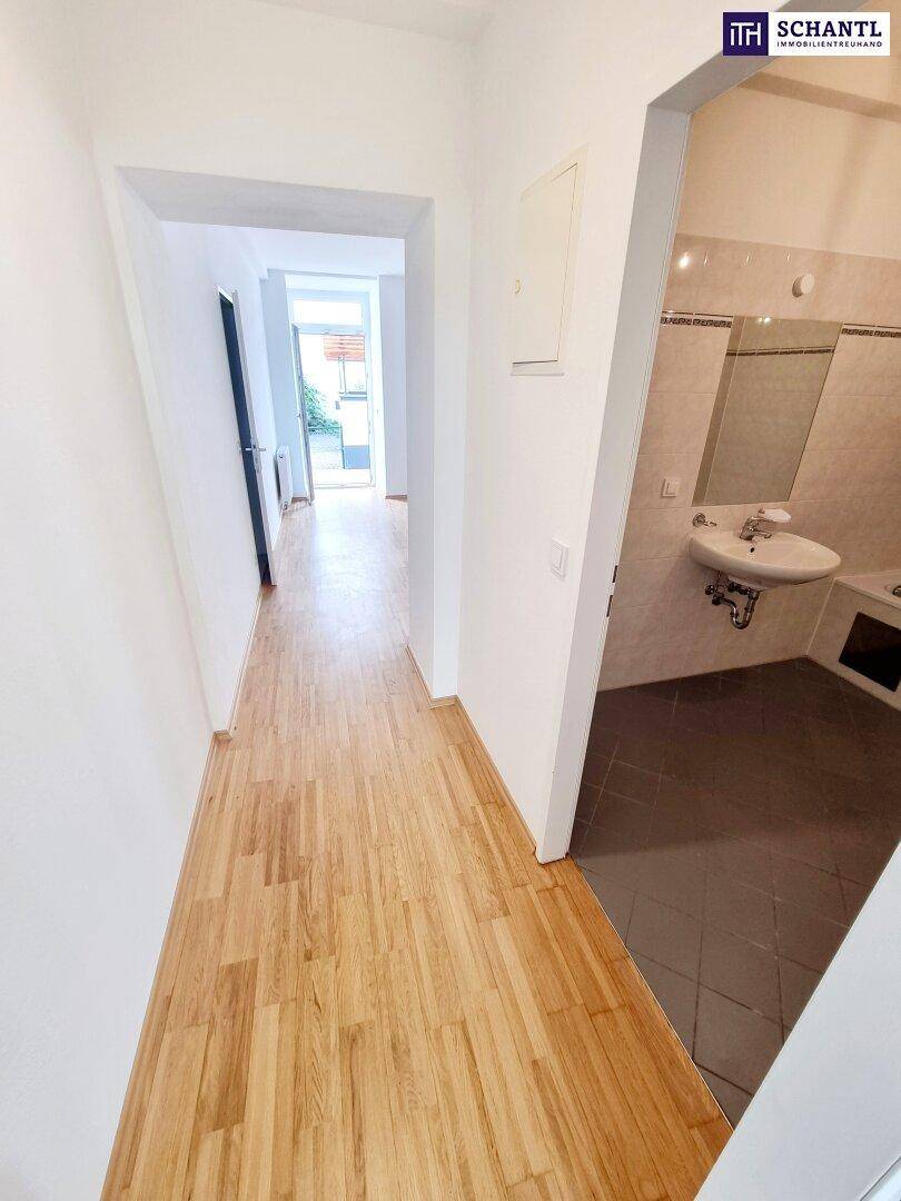 Heller Flur mit Parkettboden, der zum Badezimmer und weiteren Räumen führt.