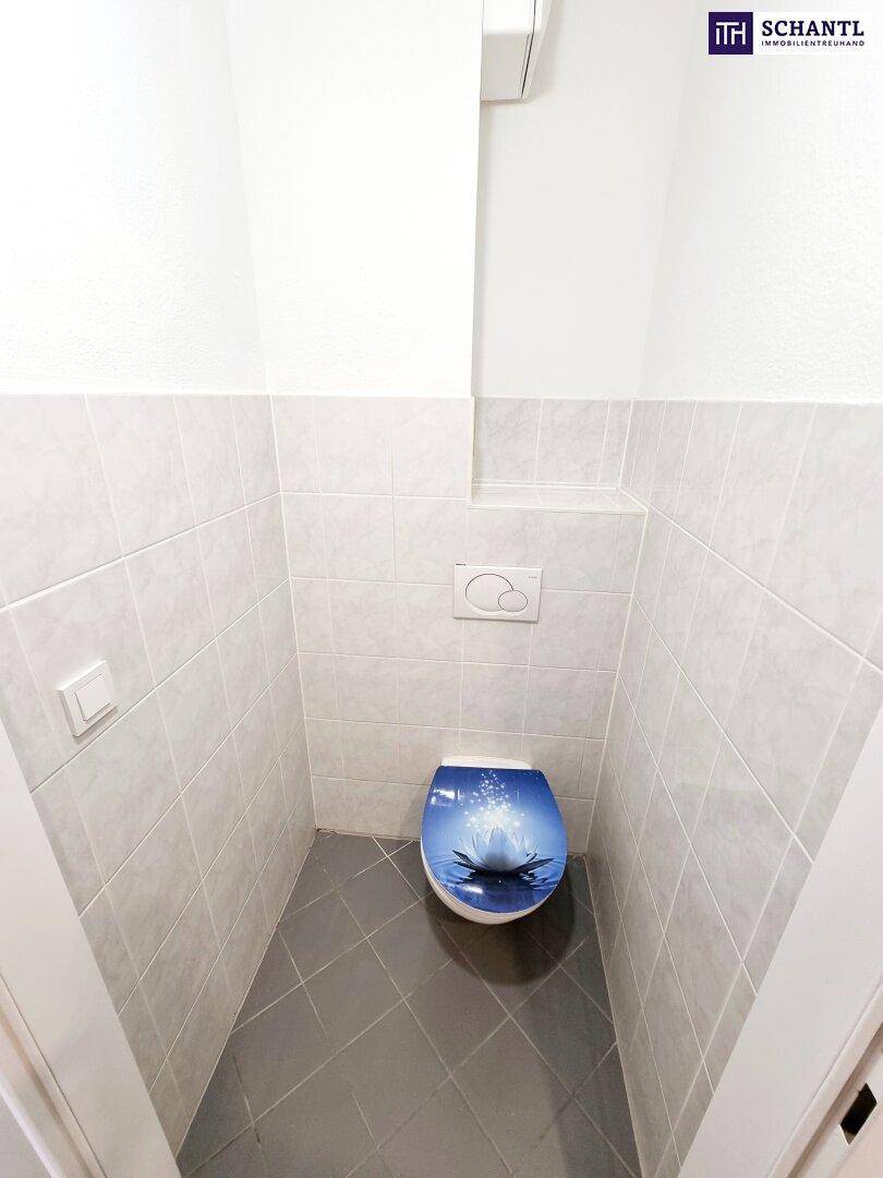 Separate Toilette mit modernem WC und Fliesenboden.