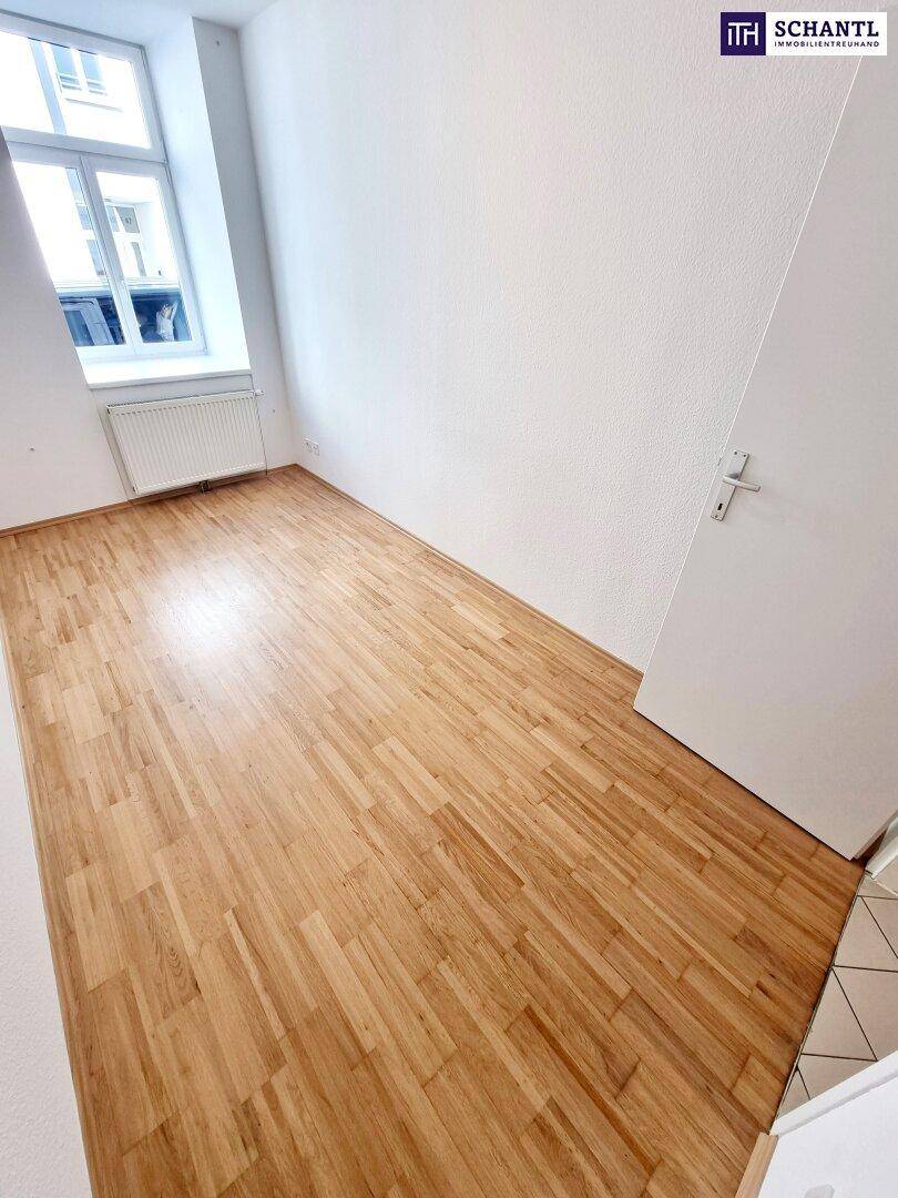 Geräumiges Zimmer mit Parkettboden und Fenster, bietet viel Tageslicht.