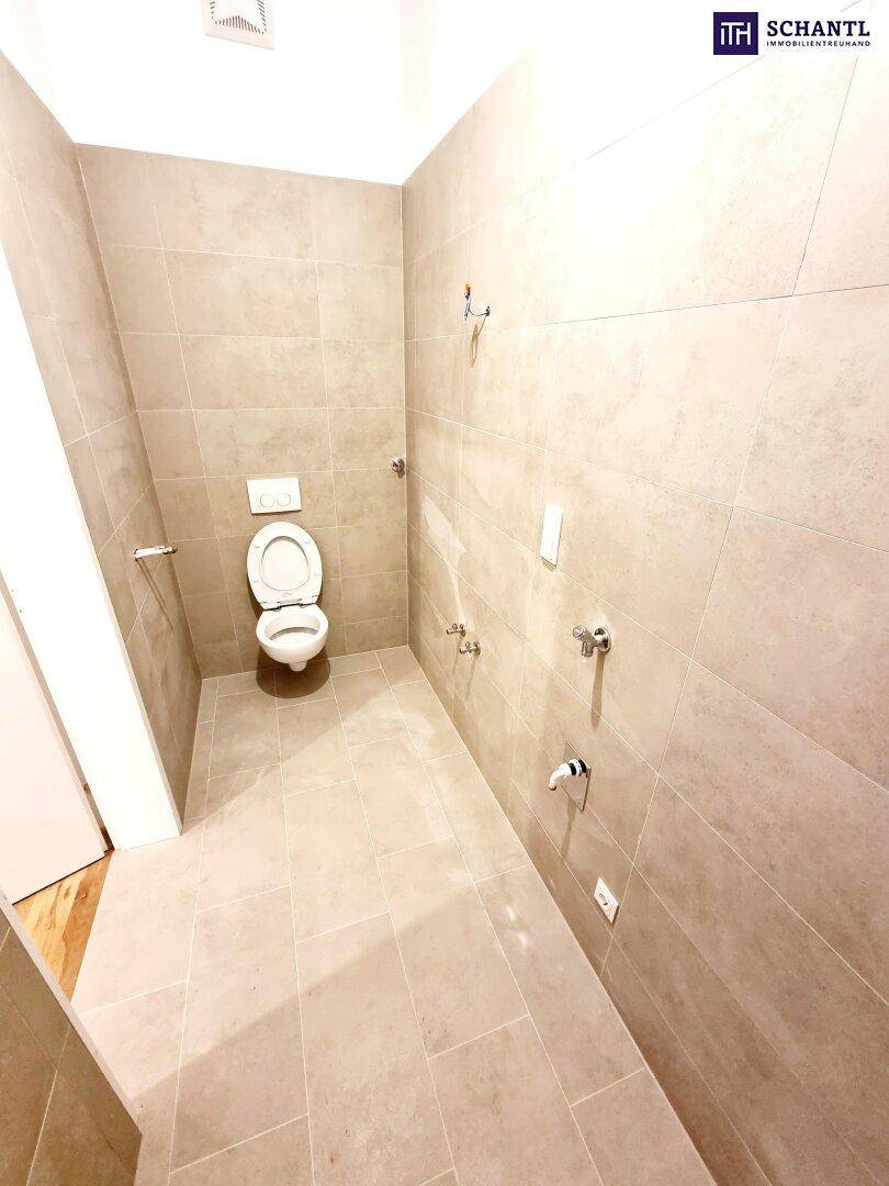 Modern gefliestes WC mit wandhängender Toilette und hellen Fliesen an Wänden und Boden.