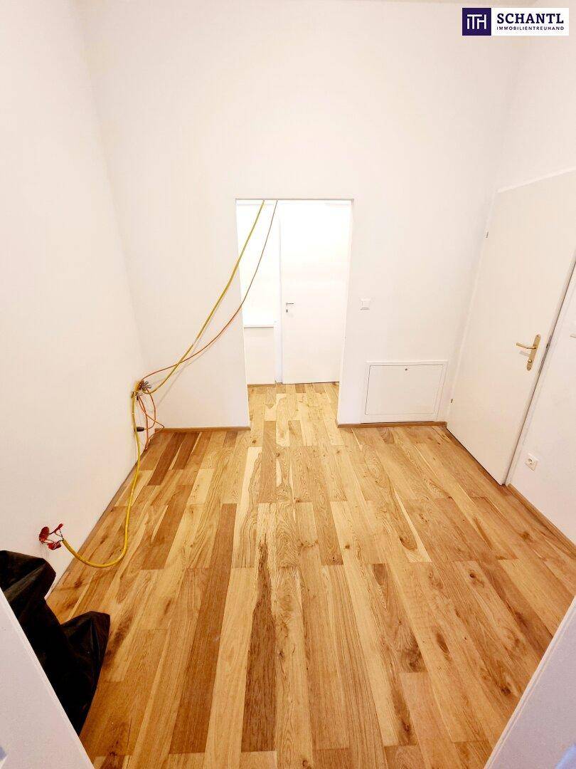 Heller Raum mit neuem Parkettboden und Kabeln an der Wand, bereit für die weitere Gestaltung.