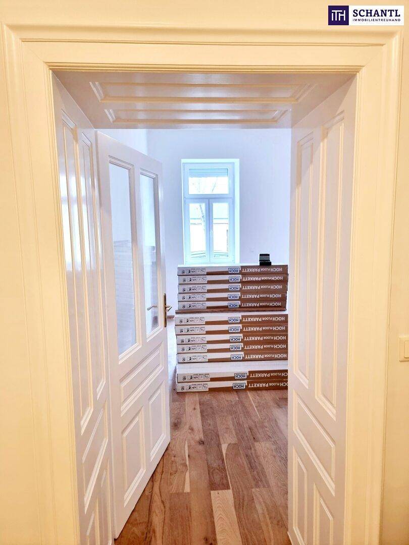 Offene Doppeltür mit Glaseinsätzen, die den Blick auf einen hellen Raum mit Parkettboden freigibt.