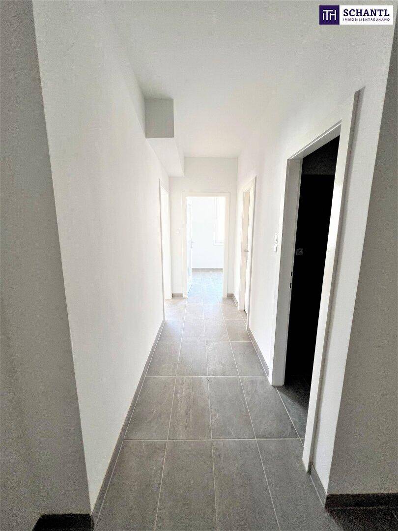 Geräumiger Flur mit grauen Fliesen und mehreren Türen, die zu weiteren Räumen führen.