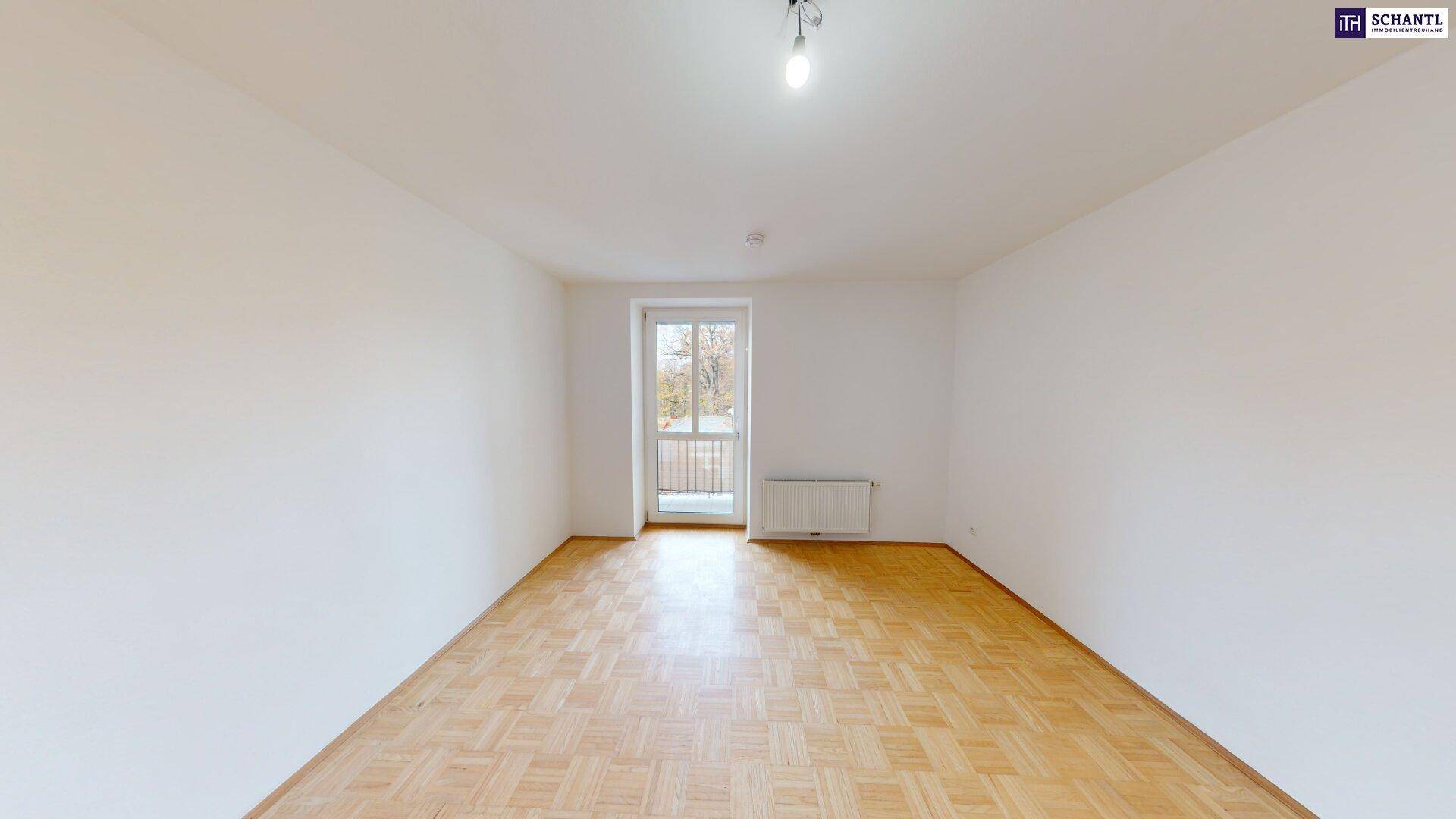 Helles Schlafzimmer mit Parkettboden und einem Fenster, das einen Blick ins Grüne bietet.