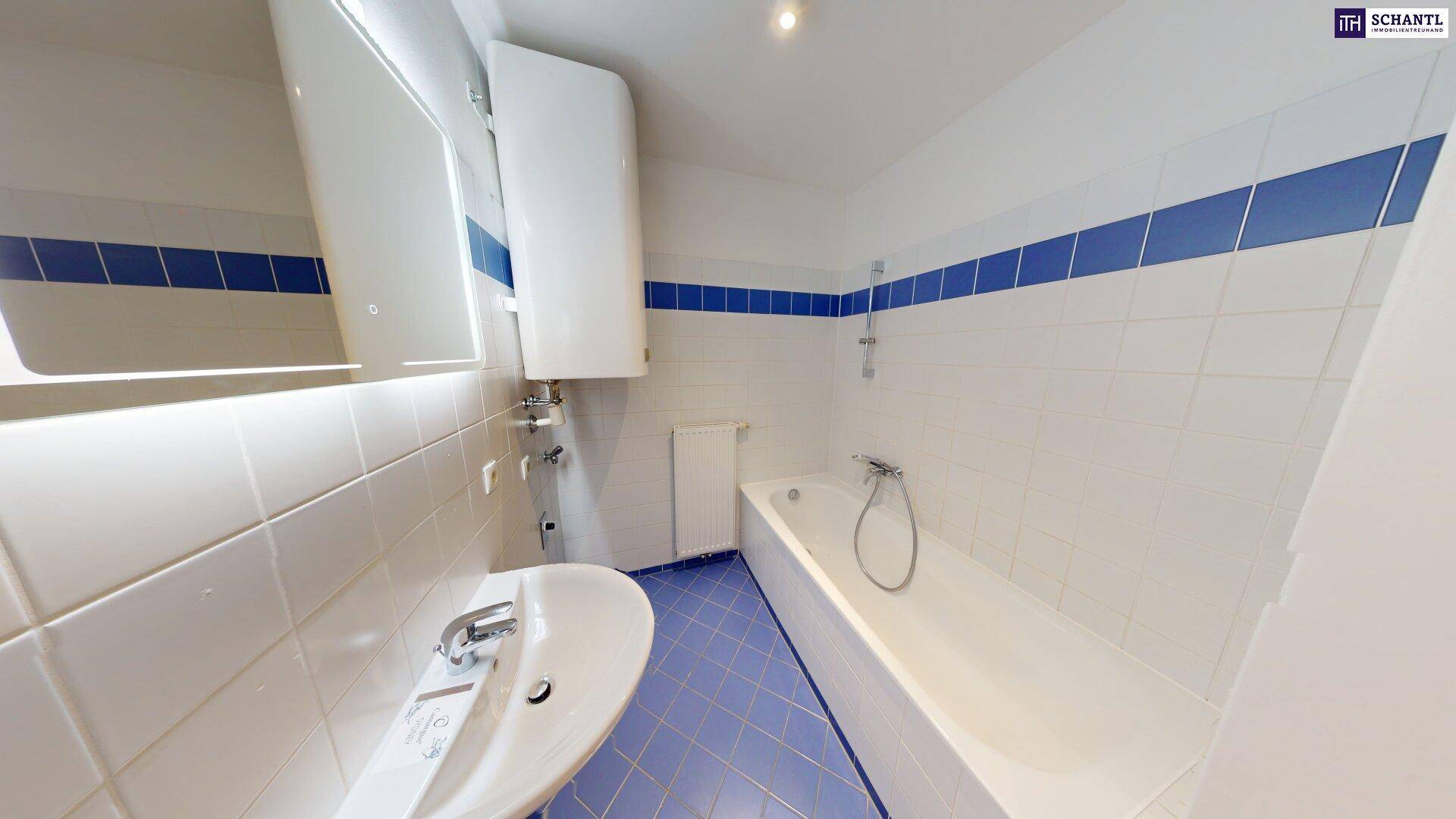 Badezimmer mit Badewanne, Waschbecken und Spiegel, ausgestattet mit blauen und weißen Fliesen.