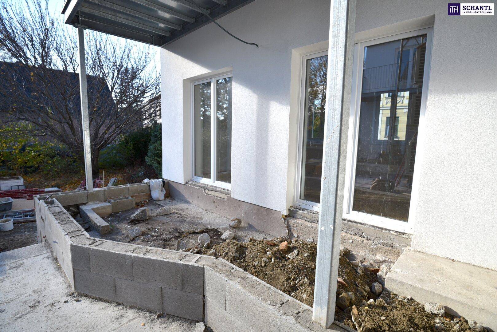 Außenbereich im Bau mit neuen Fenstern und vorbereitetem Fundament für eine zukünftige Terrasse.