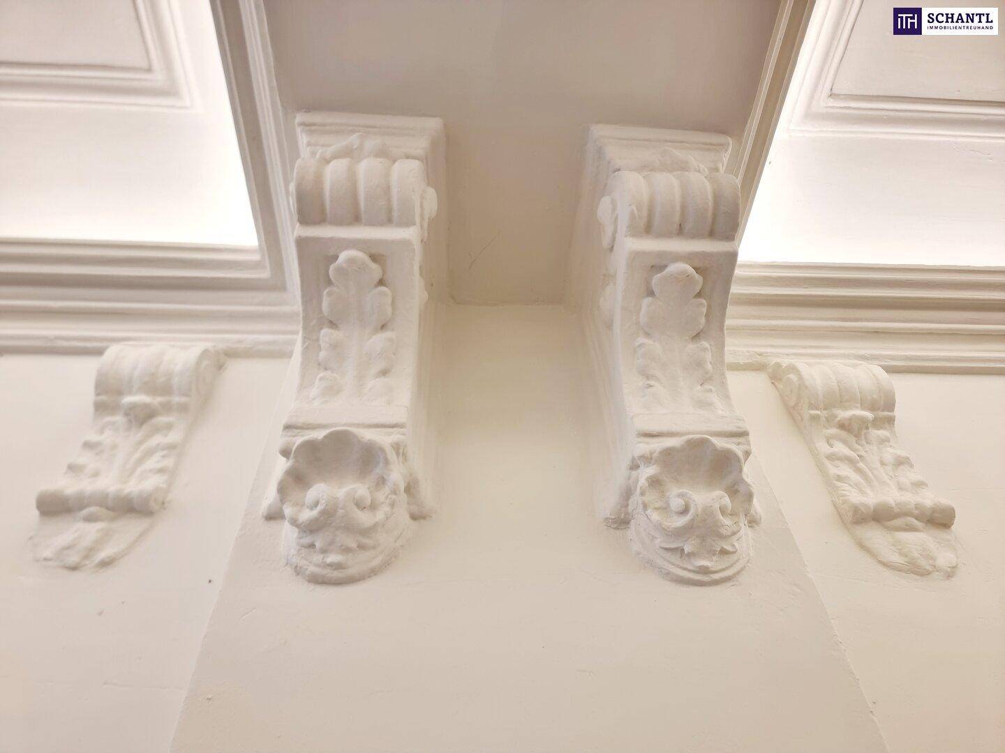 Detailaufnahme der dekorativen Stuckkonsolen an der Decke eines historischen Gebäudes.
