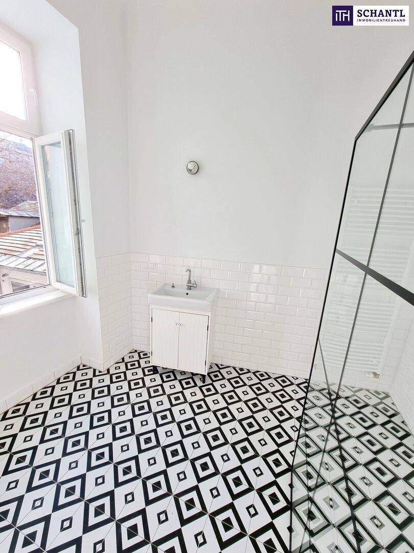 Helles Badezimmer mit gemusterten Bodenfliesen, Duschkabine und Fenster mit Blick nach draußen.