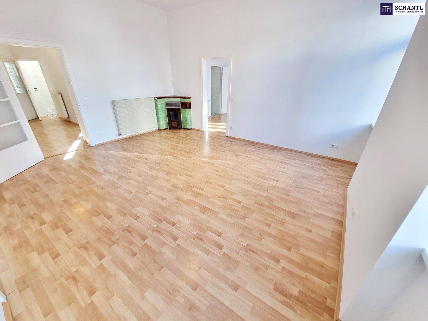 Geräumiges Wohnzimmer mit Laminatboden, einem traditionellen Ofen und viel Tageslicht.